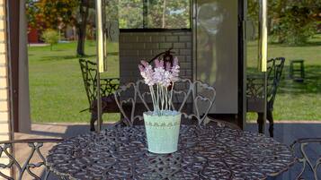 Un patio con una mesa redonda, sillas y un florero decorativo.