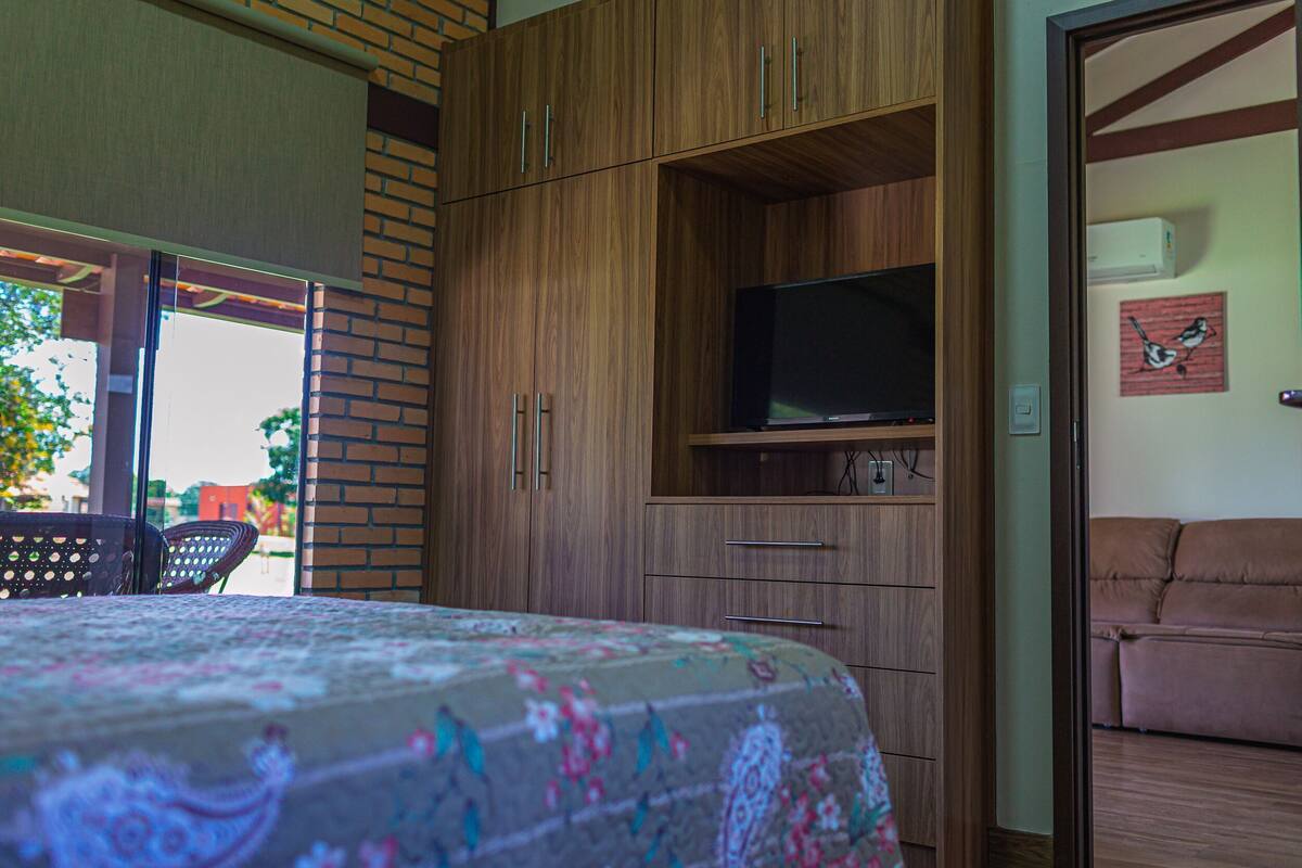 A bedroom with a bed, wooden wardrobe, television, and a sofa.