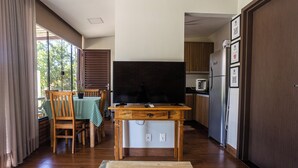 A compact kitchen with a wooden table, a flat-screen TV, and a refrigerator. - Villaggio dos Pássaros (Paranoa)