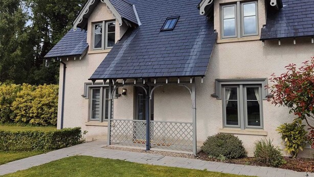 Une maison à deux étages, dotée d’un toit à pignon, d’un porche abrité et d’une pelouse bien entretenue.