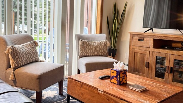 A living room with two armchairs, a coffee table, a television, and a cabinet.