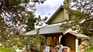 A house with a covered porch, outdoor seating, and stacked firewood. - Big Sky Bungalow - Center of Big Sky (Big Sky)