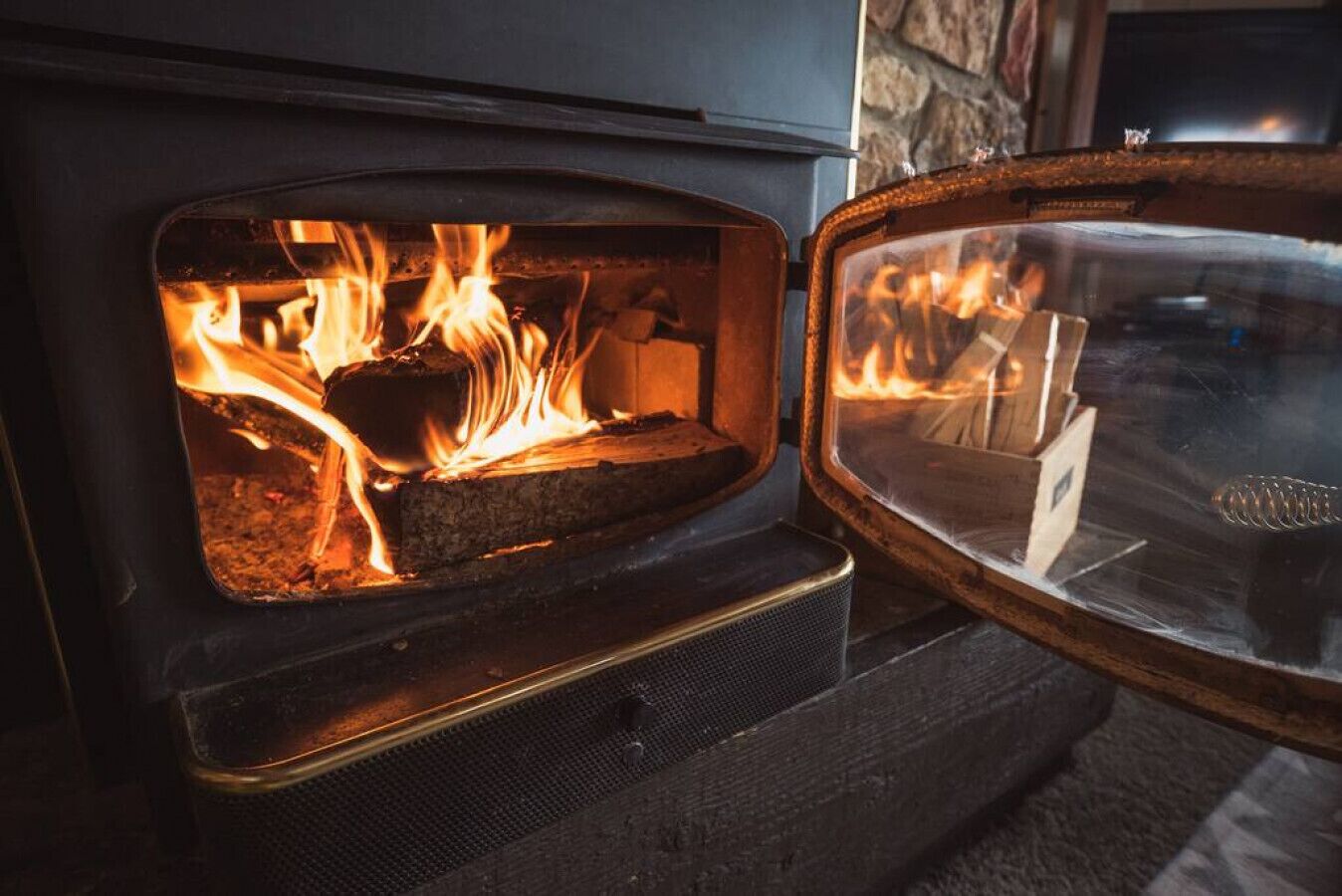 Un poêle à bois avec des flammes apparentes et une porte en verre.