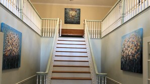 Een trap met witte balustrades en houten treden die uitkomen op een plateau.