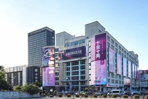 A modern building with large digital billboards, a prominent entrance, and a parking lot.