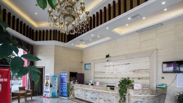 A hotel reception area with a marble reception desk, a chandelier, and a television screen.