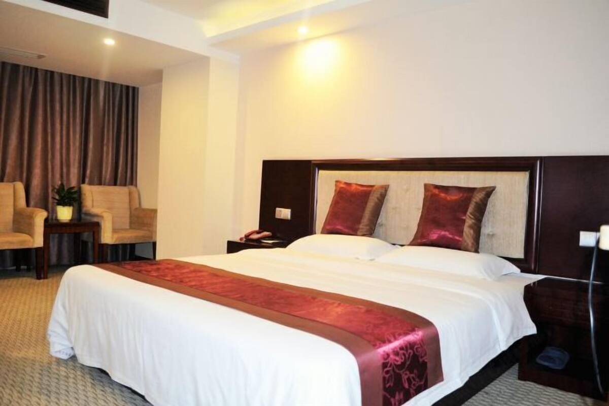 Une chambre d’hôtel avec un grand lit, deux chaises, une petite table et une table de chevet.