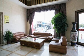A hotel lobby with leather sofas, a coffee table, a large vase, and a view of the street. - Juntai Maoshan Hotel (Tongxiang)