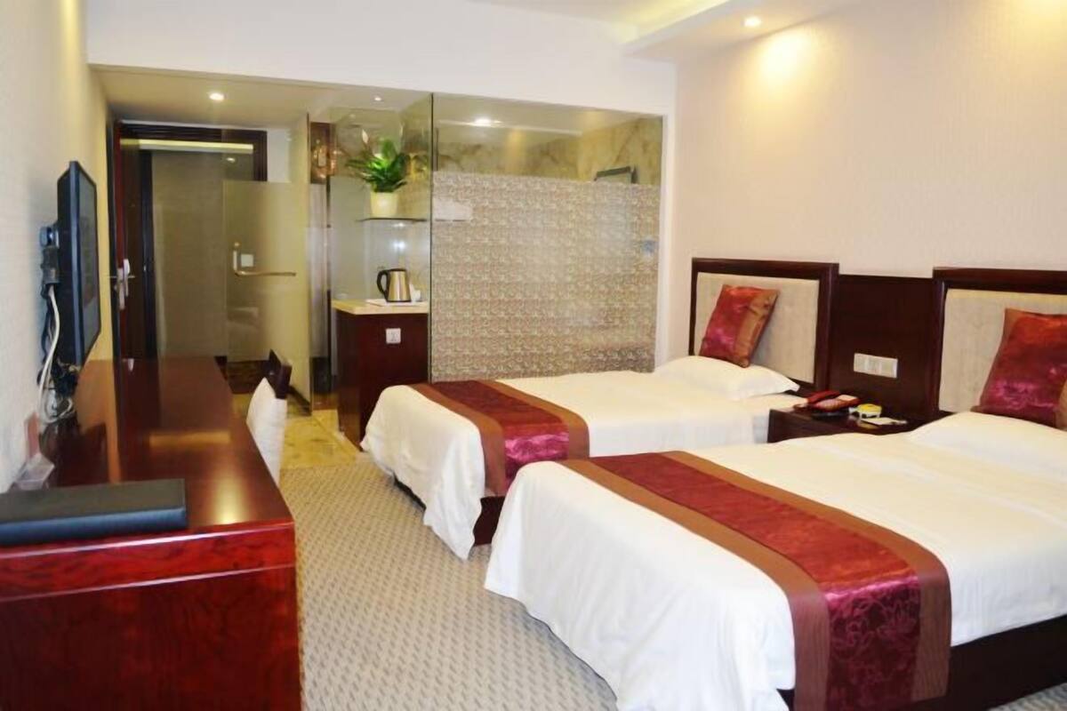 Une chambre d’hôtel avec deux lits, un bureau, une télévision et un espace douche.
