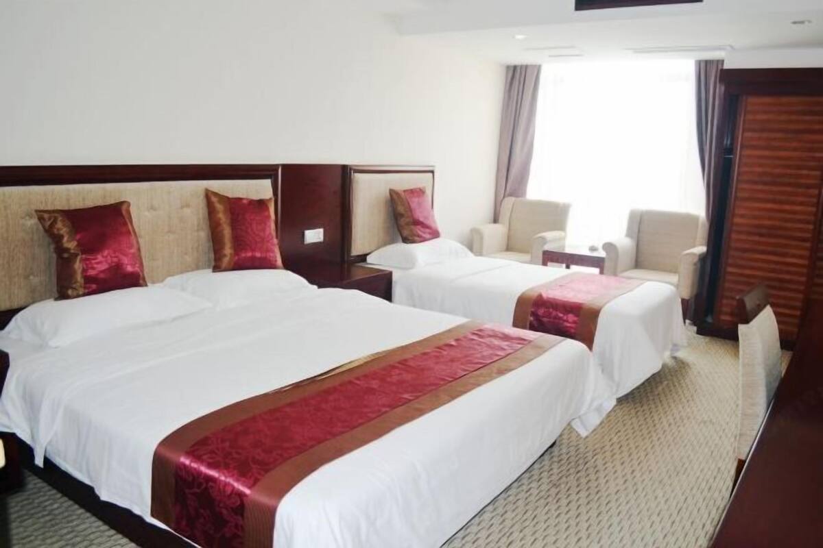 Une chambre d’hôtel avec deux lits, un coin salon et une grande fenêtre.