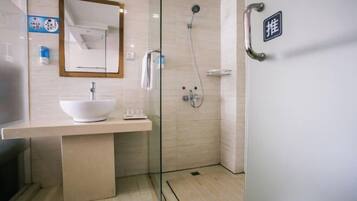 Een moderne badkamer met een douchecabine van glas, een witte wastafel en een spiegel erboven.