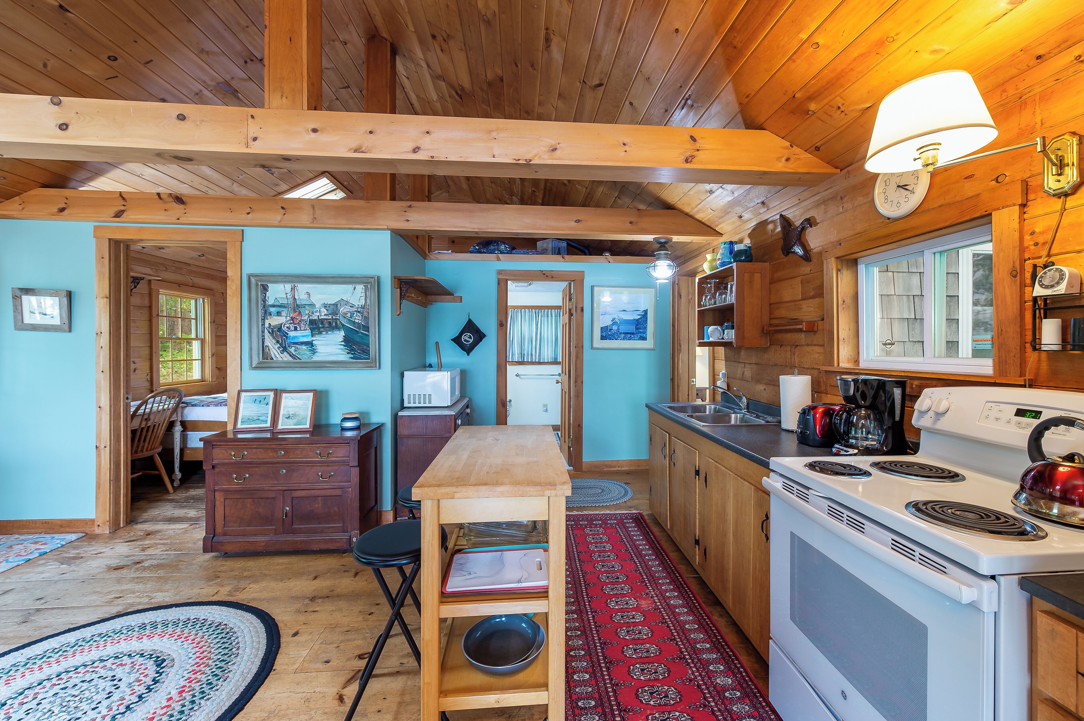 A cozy cabin-style kitchen with wooden beams, a stove, and a dining area with a table and chairs.