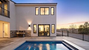 A modern two-story house with a swimming pool, a barbecue area, and a balcony.
