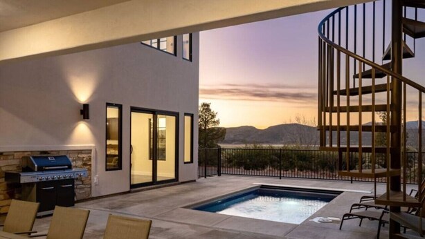 A modern outdoor patio with a pool, a barbecue area, and a spiral staircase.