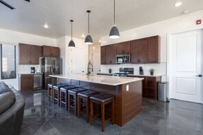 A modern kitchen with a central island, bar stools, and pendant lighting. - Impeccable destination for spending quality time with friends & family! (Hurricane)