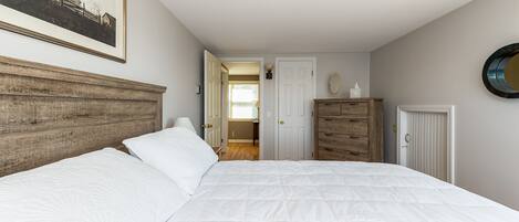 A bedroom with a large bed, wooden headboard, a dresser, and a framed picture on the wall.