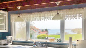 A kitchen with a large window, a sink, and a coffee maker. - Thorburn - Experience a classic ME vacation at this beautiful summer cottage (Harpswell)