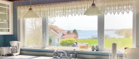 A kitchen with a large window, a sink, and a coffee maker.