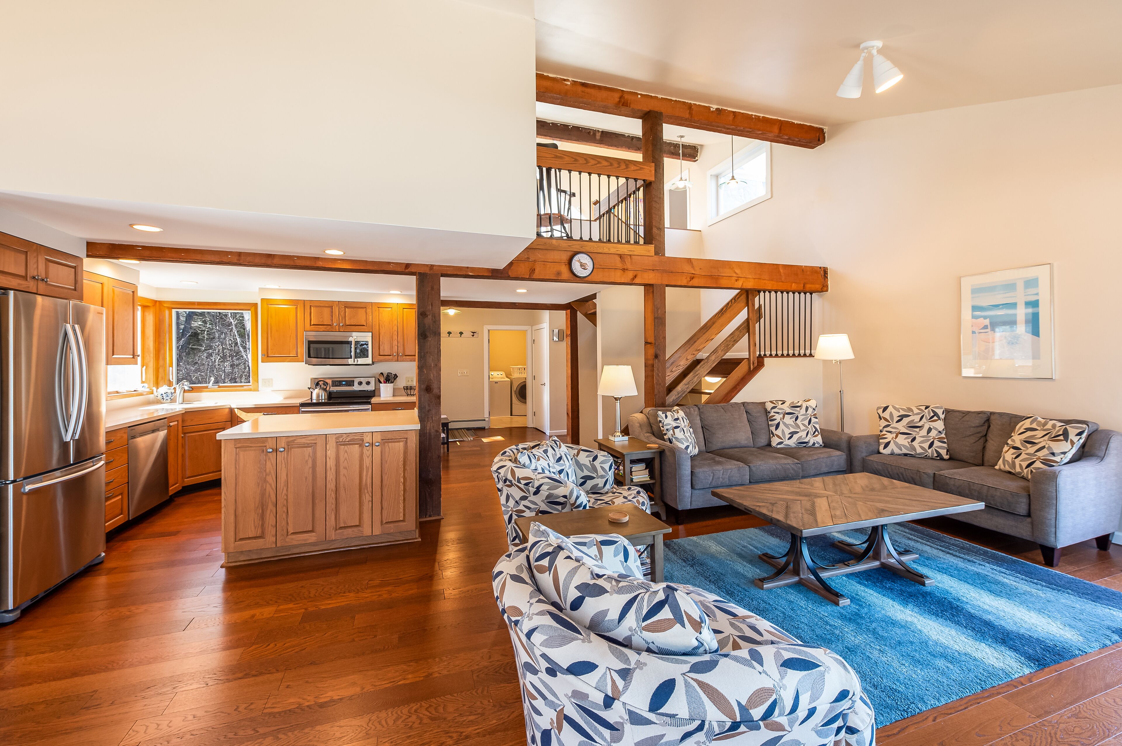 A spacious living area with a large sofa set, a coffee table, and a blue rug.