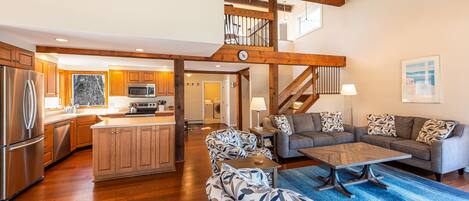 A spacious living area with a large sofa set, a coffee table, and a blue rug.