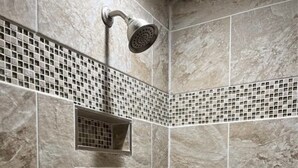 A shower area with a rain showerhead, a wall-mounted control, and a tiled mosaic border. - New Home on 5 acres, Clean, Quiet Comfortable with Private Dog Park (Columbus)