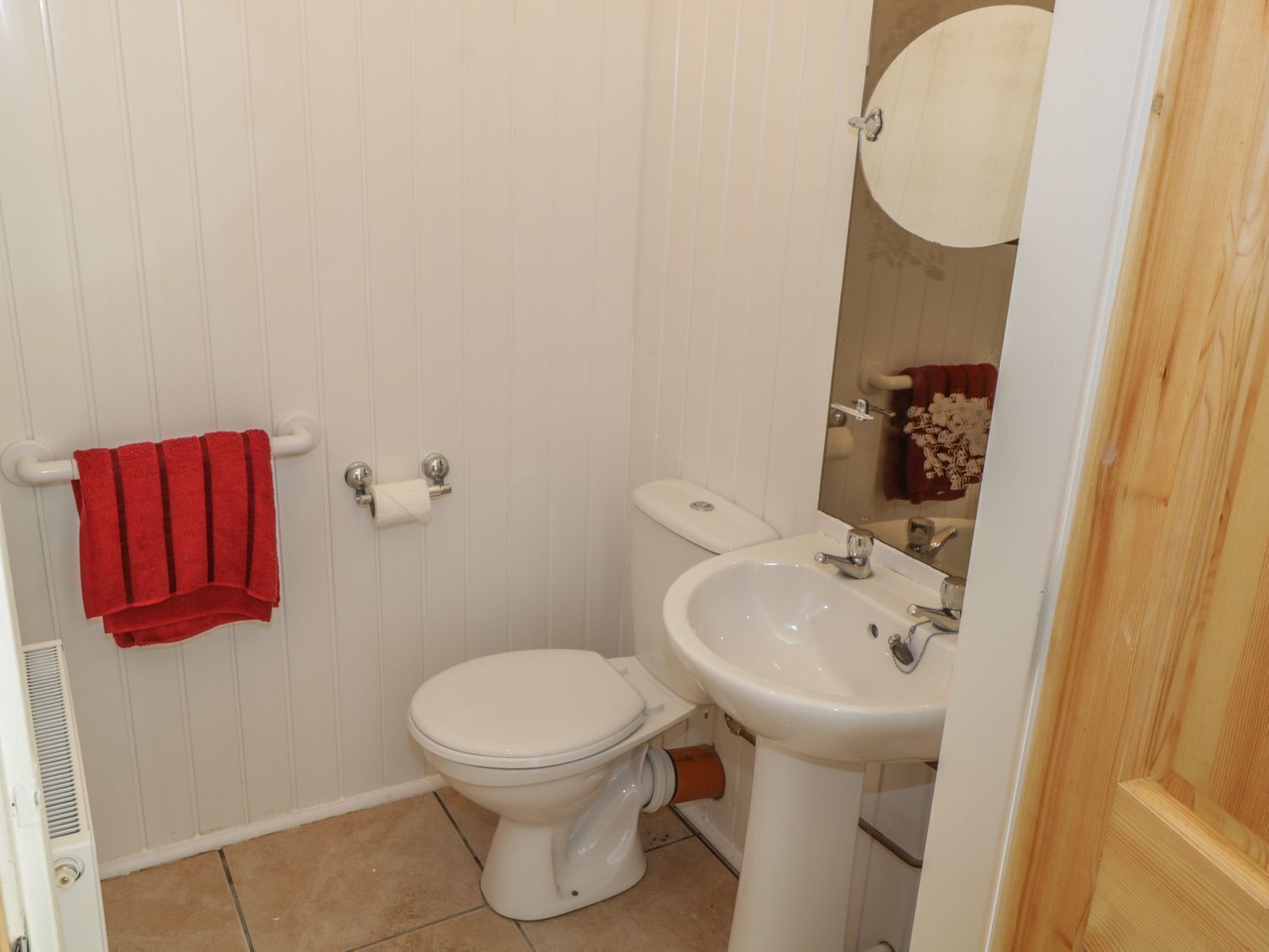A small bathroom with a toilet, sink, and a mirror.
