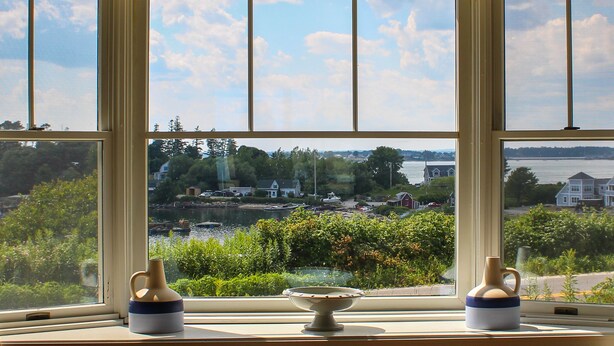 Une vue à travers une fenêtre, avec deux vases posés sur le rebord.