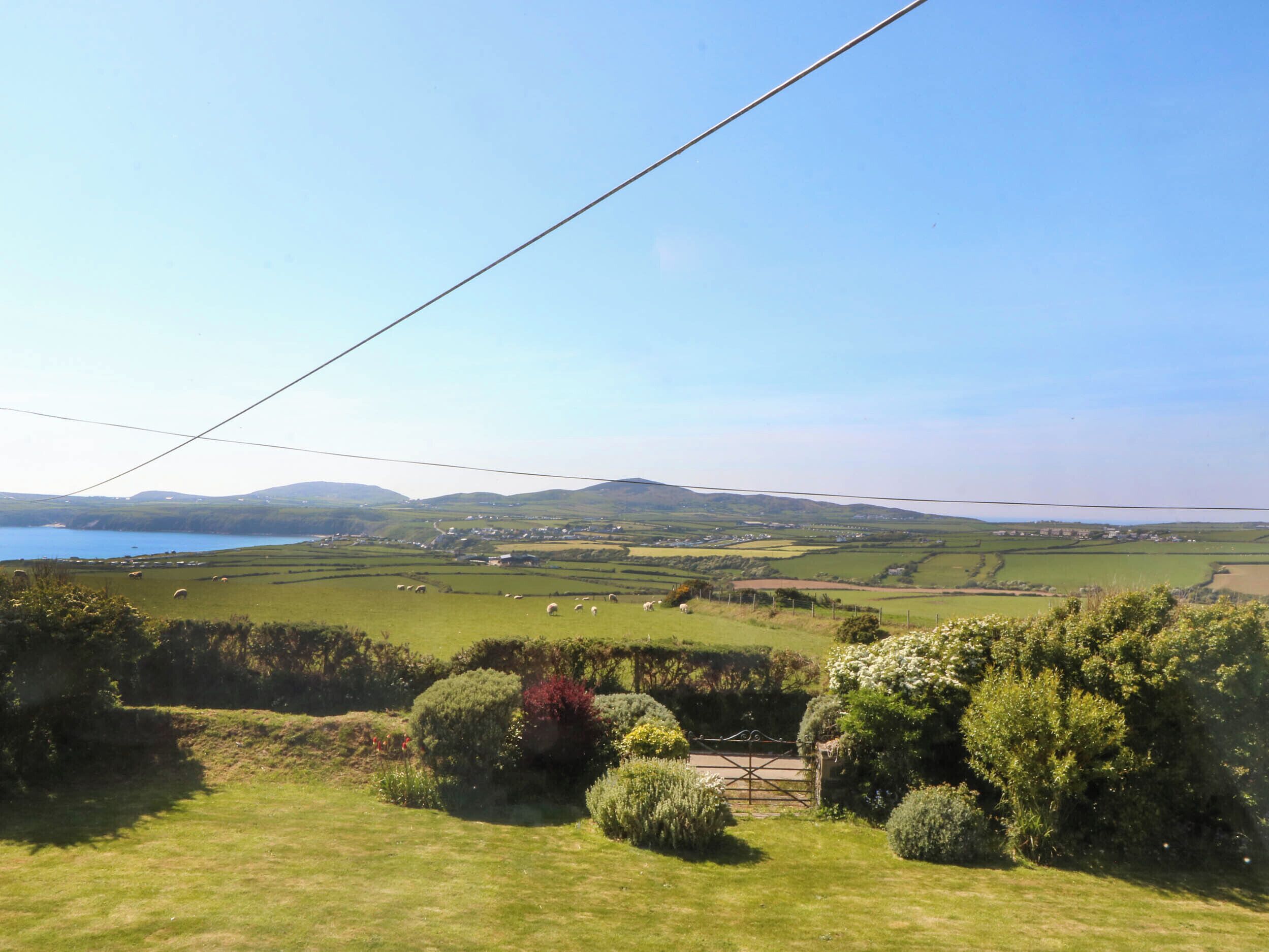 A rural landscape with a clear view of a lake, rolling hills, and a few scattered houses.