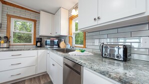 Une cuisine moderne avec des meubles blancs, un plan de travail en granit et un grille-pain encastré.