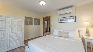 Une chambre à coucher comprenant un lit, une table de chevet, une commode et des œuvres d’art murales.