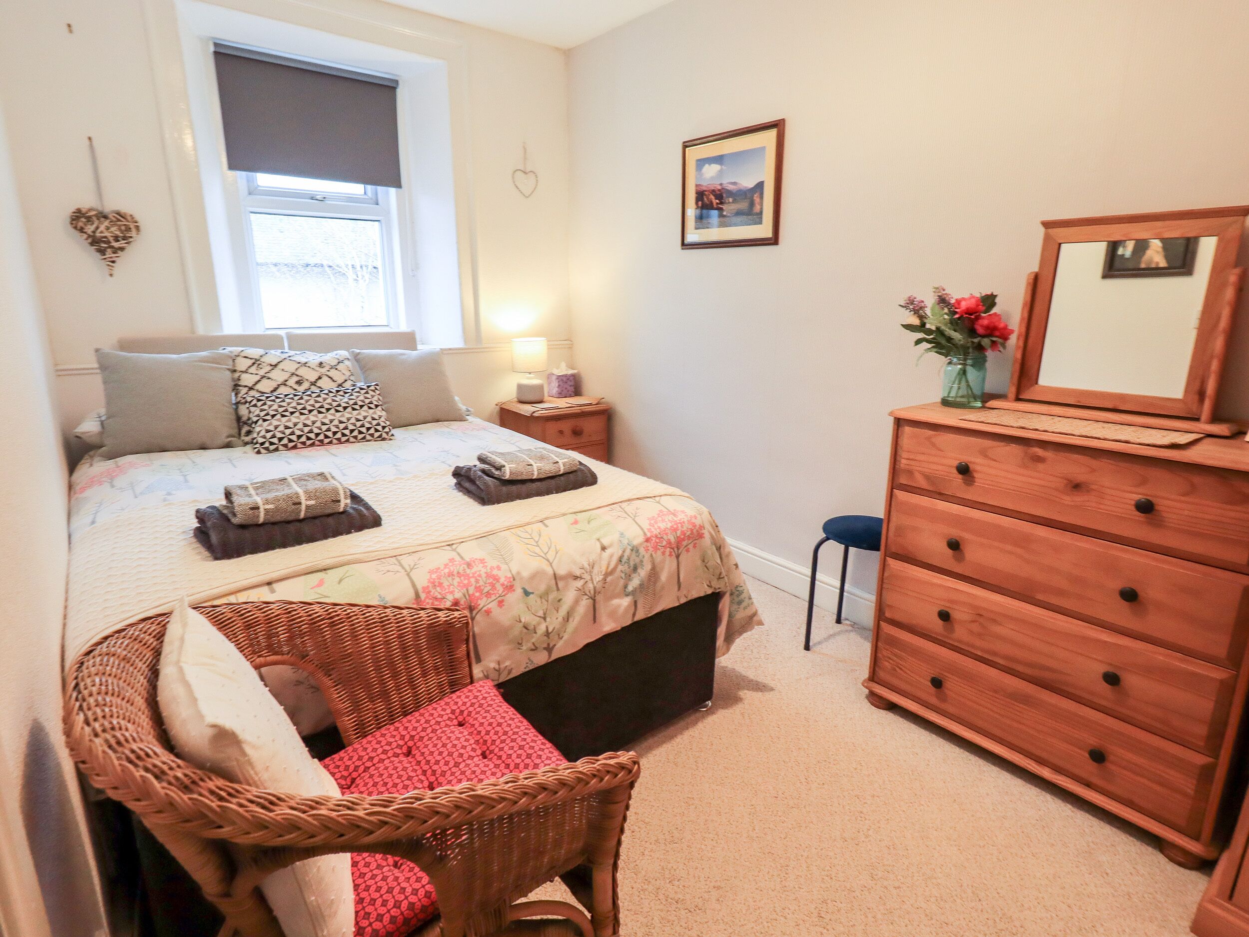 A bedroom with a bed, bedside tables, a dresser, a chair, and a window.