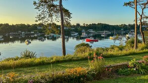 Vista de un lago con barcos, árboles y un área verde con flores.
