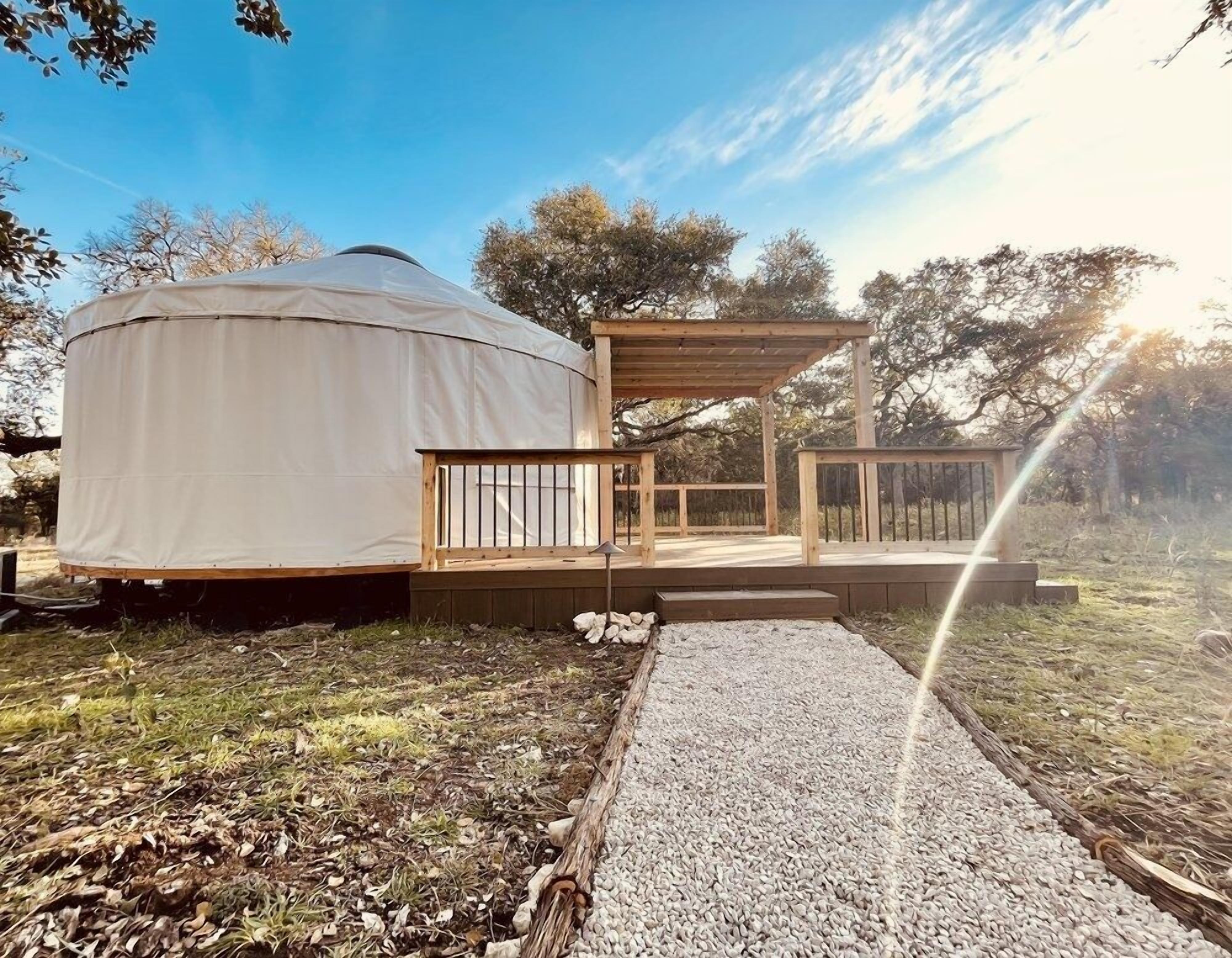 Una yurta con terraza de madera y zona de estar cubierta al aire libre.
