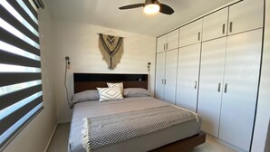 Una camera da letto con un letto, una ventola a soffitto, un armadio e una finestra con persiane.