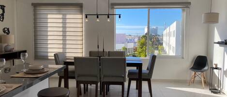 A modern kitchen with a dining area, large windows, and a view of the city.