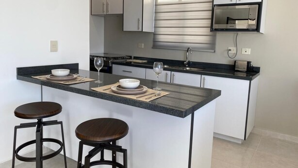 Una cucina moderna con isola centrale, sgabelli da bar e forno integrato.