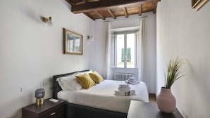 A bedroom with a bed, bedside table, lamp, and a window with curtains.