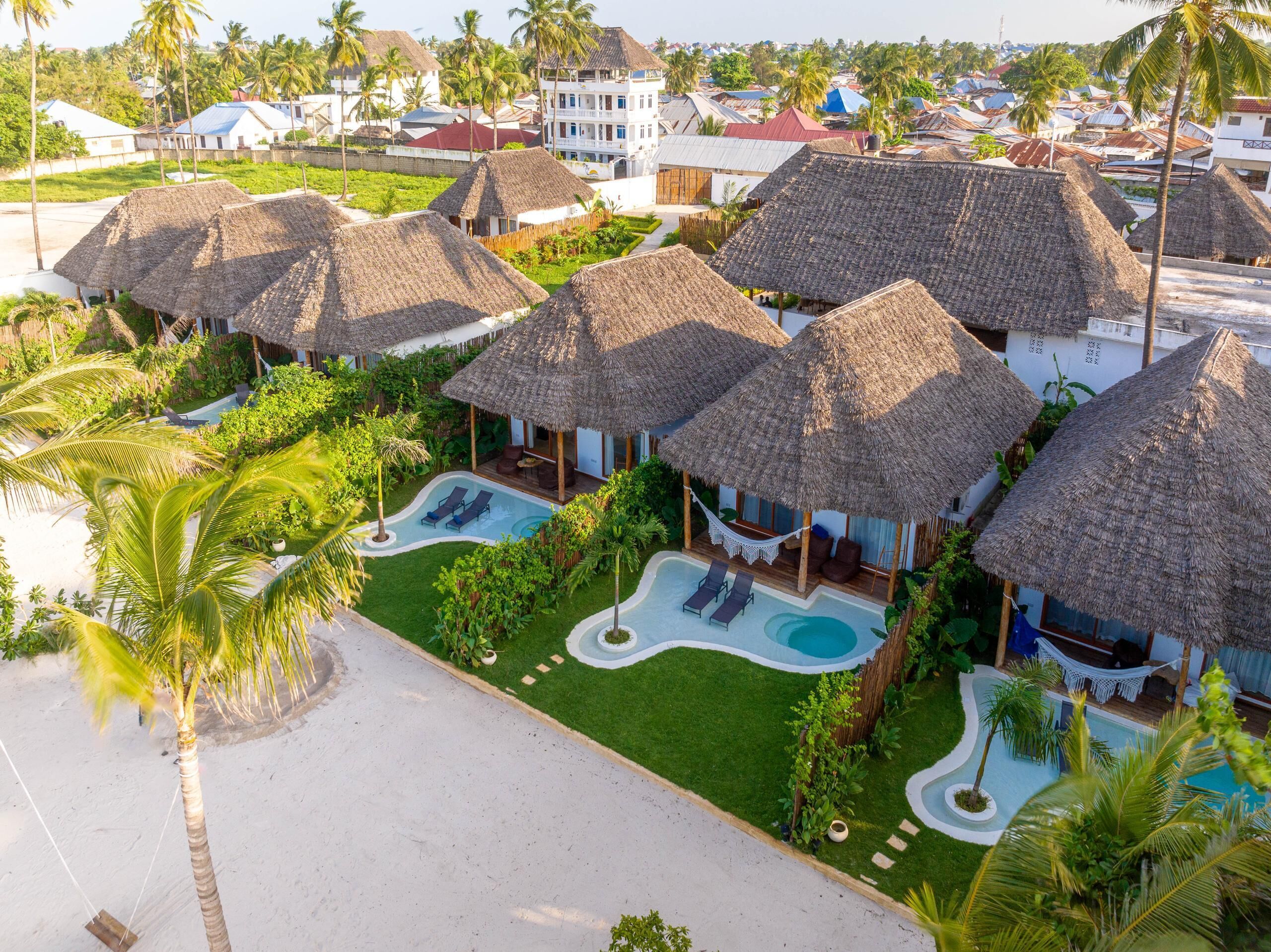Un complexe hôtelier doté de villas aux toits de chaume, d’une piscine et d’une plage.