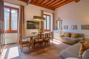 A living room with a dining table, chairs, a sofa, a TV, and a window with curtains. - Classy Apartment (Florence)