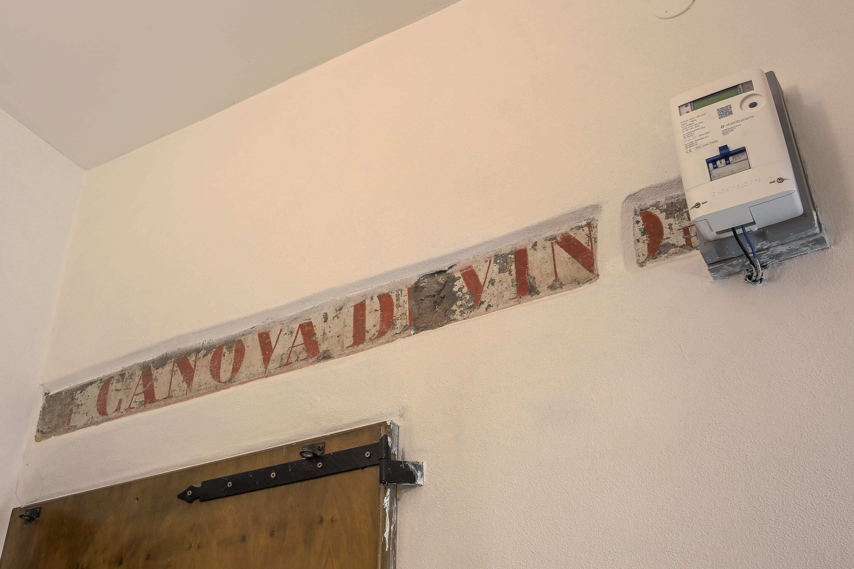 Una pared con un letrero que dice "CANOVA DIVIN" y una caja eléctrica fijada a la pared.