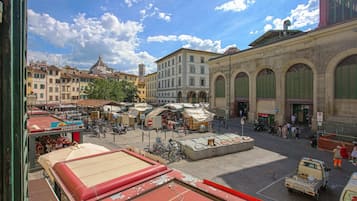 A bustling square with historic buildings, a central open space, and a pizzeria.