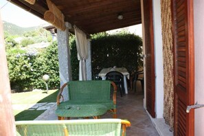An outdoor patio with wicker furniture, a table, and a chair. - PEPE house, cottage with garden 5 min from Campus beach, Villasimius  (Sardegna)