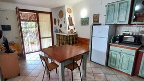 A compact kitchen with a dining table, chairs, a refrigerator, and a microwave. - PEPE house, cottage with garden 5 min from Campus beach, Villasimius  (Sardegna)
