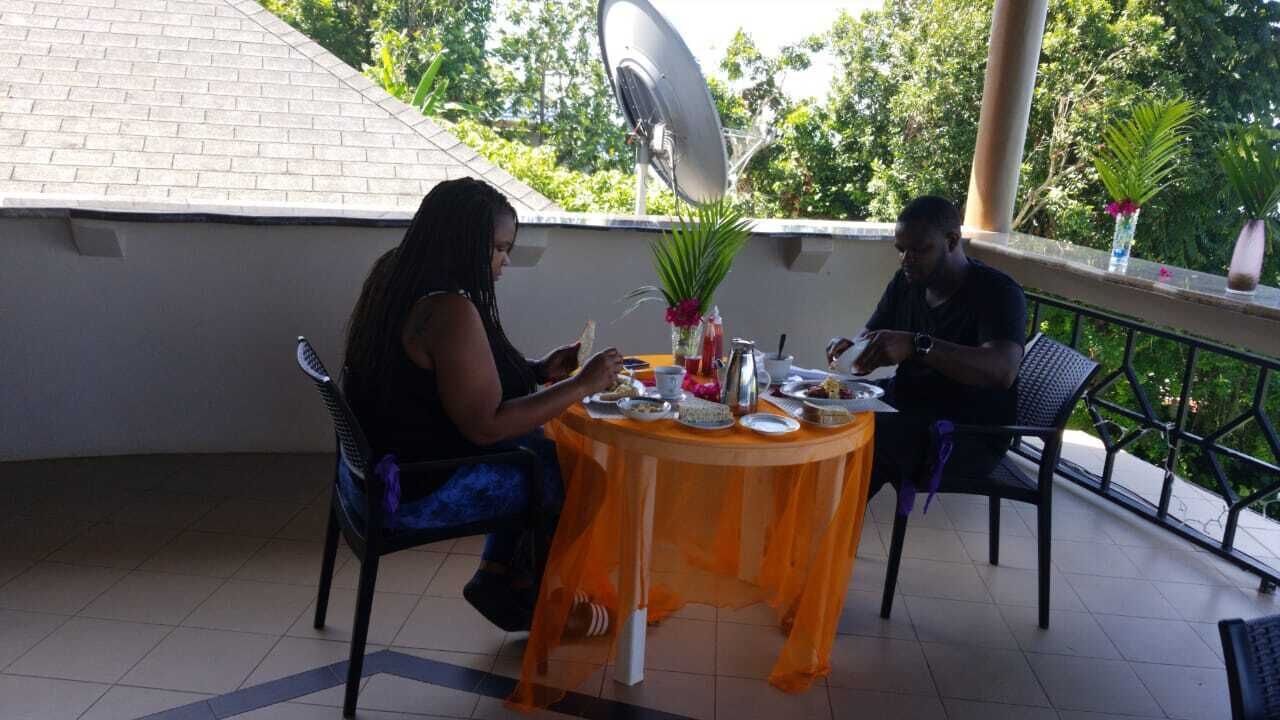 Un área de comedor al aire libre techada con una mesa dispuesta para dos, rodeada de sillas, y una antena parabólica en lo alto.