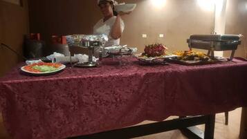 A buffet table with various dishes and a person serving food.