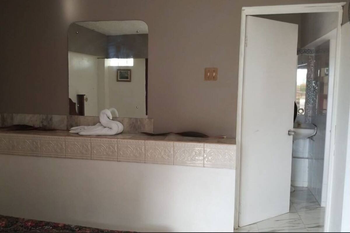 A bathroom with a white vanity, a large mirror, and a towel on the counter.