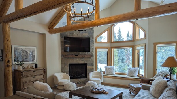 A spacious living room with a stone fireplace, large windows, and wooden beams. - Quiet and Charming Big Sky home (Big Sky)