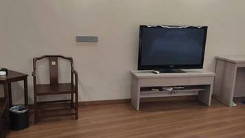A room with a television on a stand, a wooden chair, and a small table.