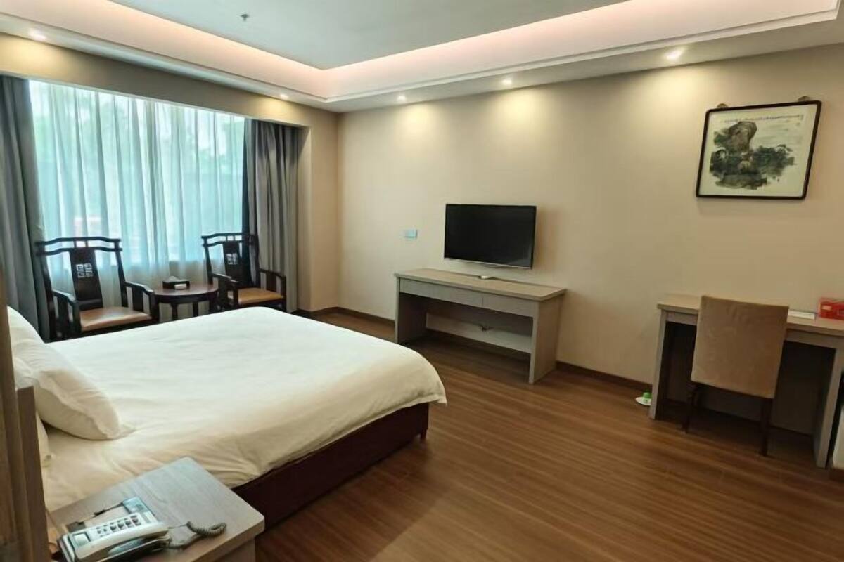 A hotel room with a bed, a desk, a TV, and a chair.