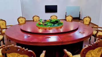 Un salón de conferencias con una mesa redonda, sillas y un televisor de pantalla plana en la pared.